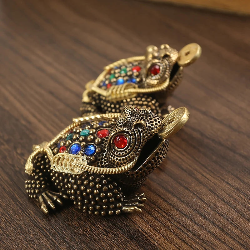 Figurita de sapo chino dorado con piedras preciosas coloridas, sobre una superficie de madera oscura.