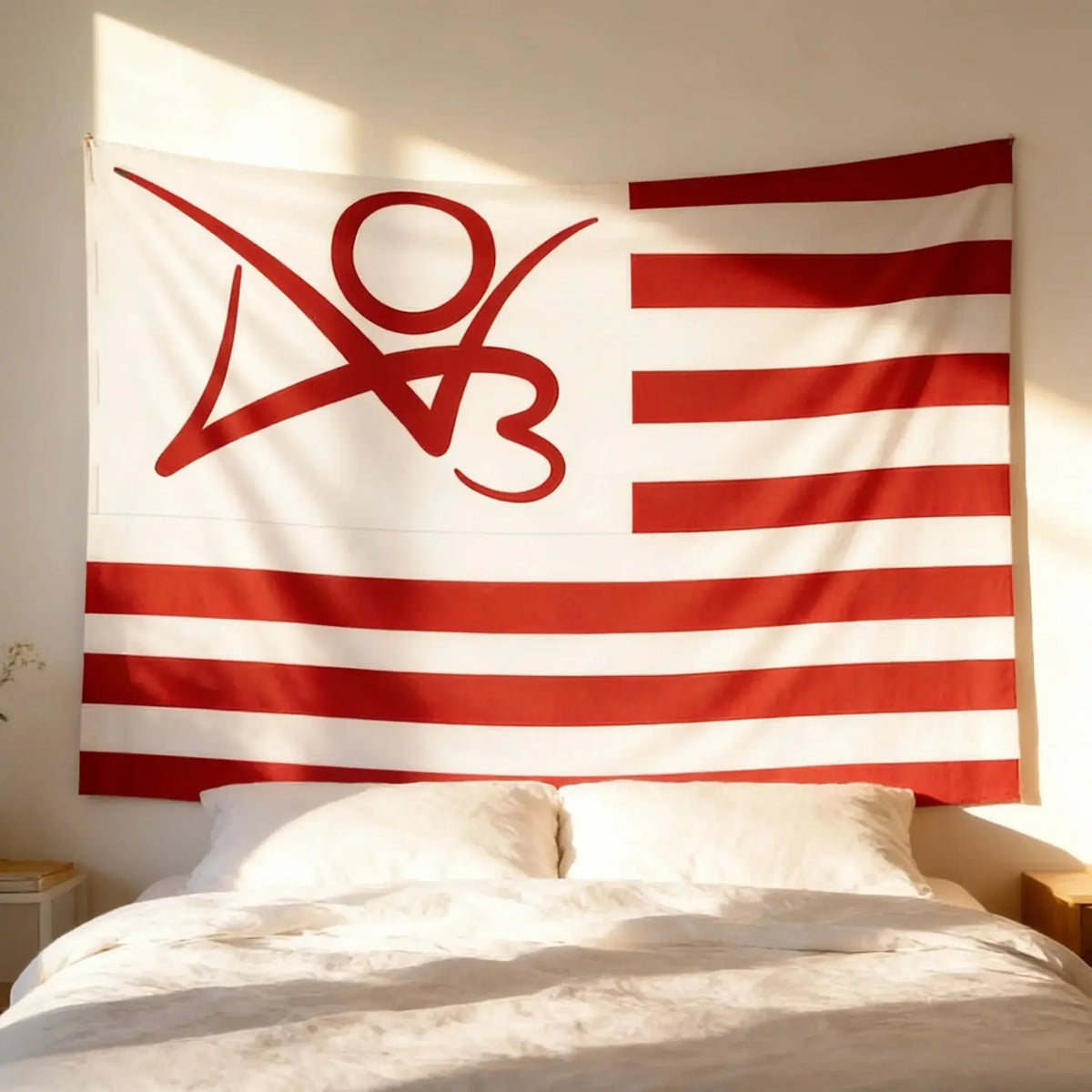 Une tapisserie en tissu blanc avec un drapeau rayé rouge et un logo rouge stylisé sur un mur clair.