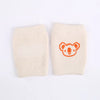 A pair of beige knitted knee pads with an orange bear face design.
