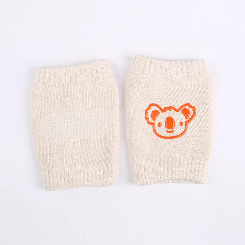 A pair of beige knitted knee pads with an orange bear face design.