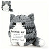 A gray knitted cat plush pendant with a pink nose and an attached card encouraging positive self-belief.