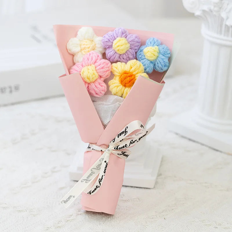 A pink handmade crochet flower bouquet featuring purple, yellow, and blue velvet blooms.
