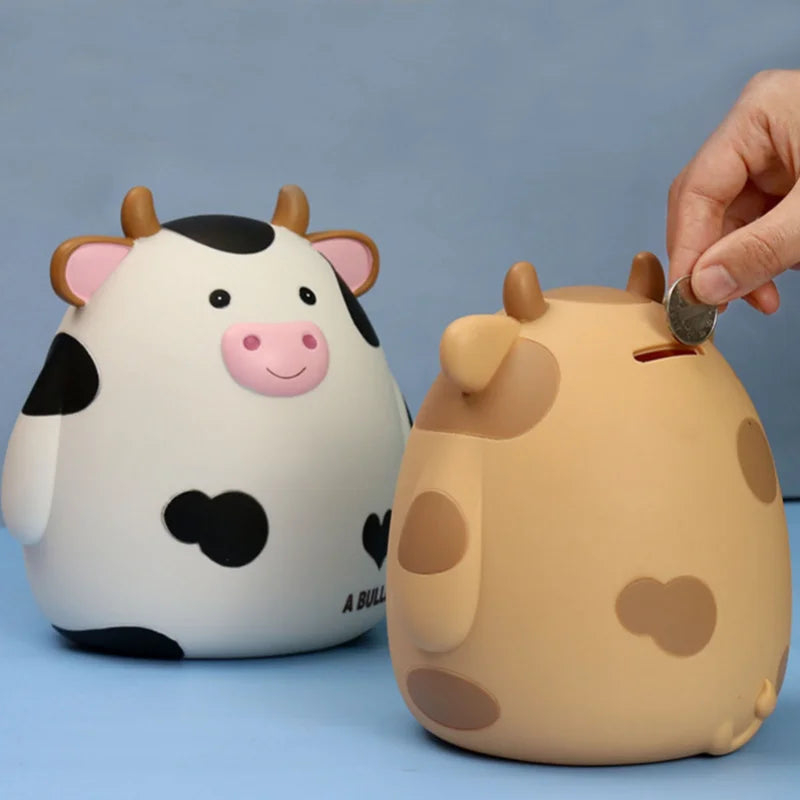 A cute, light-colored cow piggy bank with black spots is being held by a hand.