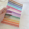 A grid of colorful glitter gems arranged in rows and columns for facial tattoos.