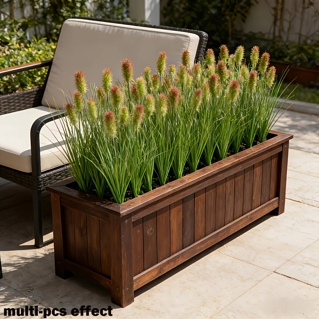 A wooden planter filled with artificial grass stems and a wicker outdoor chair in a garden setting.