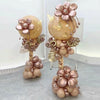 A display of pink and gold metallic balloons arranged in a column stand with floral accents.