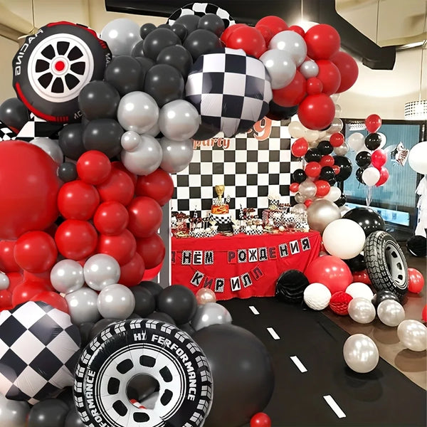 A balloon garland arch featuring red, black, and white latex balloons shaped like tires and spheres.