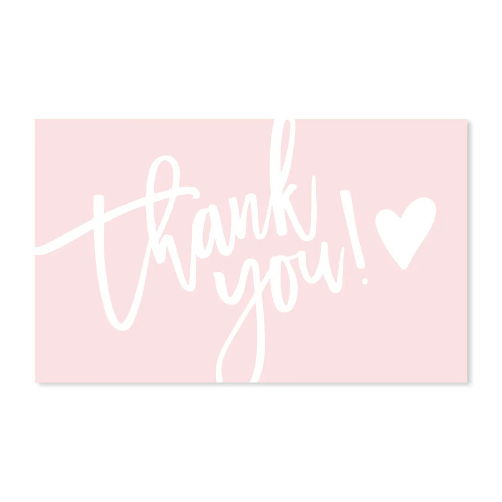 A pink card with white cursive text that reads Thank you and includes a heart symbol.