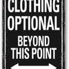 A black metal sign with white text that reads CLOTHING OPTIONAL BEYOND THIS POINT and an arrow pointing left.