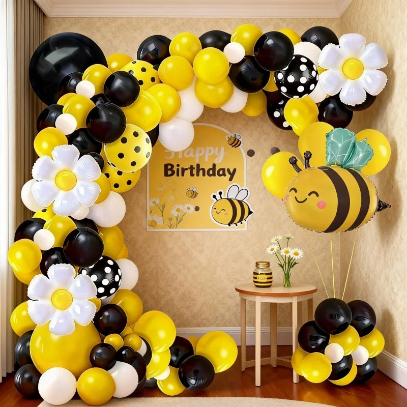 A yellow and black balloon arch set featuring bees and daisies against a light background.