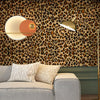 A living room wall covered in leopard print wallpaper featuring a modern gold floor lamp and a light-colored sofa.