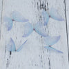 Light blue organza butterfly embellishments scattered on a white wooden surface.