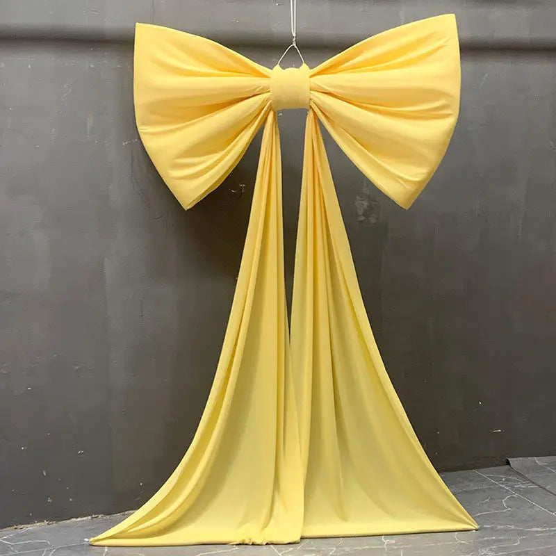 A bright yellow satin bow with long tulle drapes, used for event decoration.