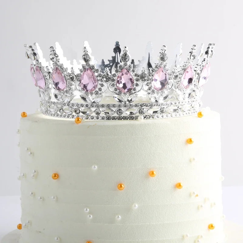 Gâteau à étages blanc décoré d'une couronne en métal scintillant avec des gemmes roses.