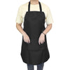 A person wearing a black waterproof kitchen apron with a front pocket over a light yellow shirt.