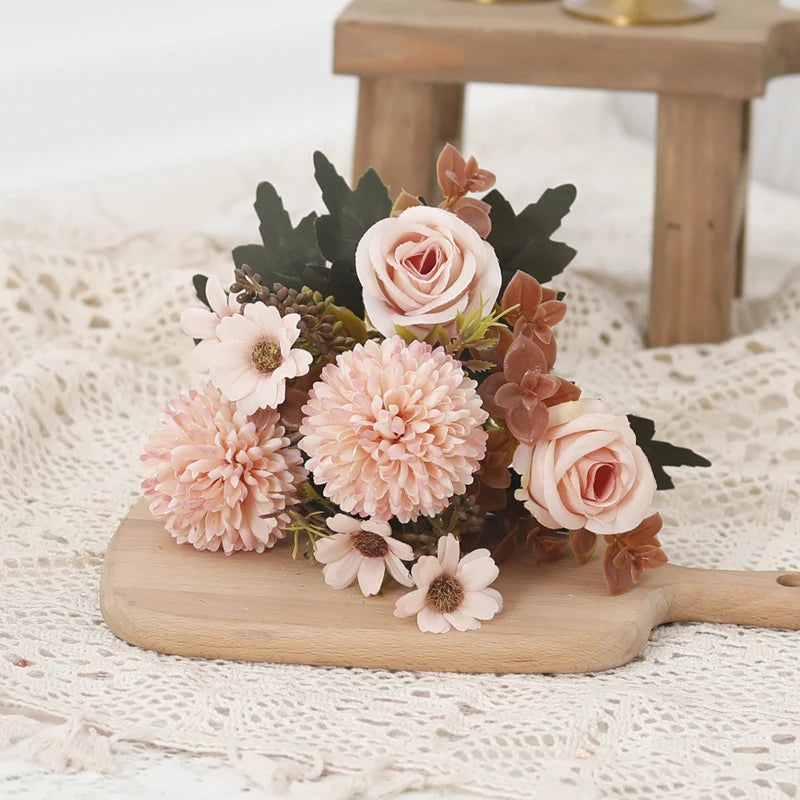 A bouquet of pink and peach roses and hydrangeas with dark green foliage displayed on a wooden board.