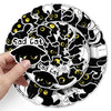 A hand holds a circular sticker design featuring multiple sad black cats with yellow eyes.