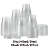 A collection of clear plastic sauce cups and lids in various sizes stacked on a white background.