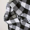 Close-up of a men's black and white plaid flannel shirt sleeve showing the fabric texture and button detail.