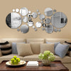 A wall display featuring a collection of round acrylic mirror stickers in various sizes and finishes on a beige wall.