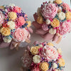 A collection of pink, yellow, and white floral silicone candle molds shaped like roses, peonies, and camellias.