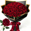 A bouquet of 50 deep red velvet touch artificial roses presented in a black and gold wrapping.