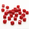 A pile of small, square-cut red glass crystal beads for jewelry making.