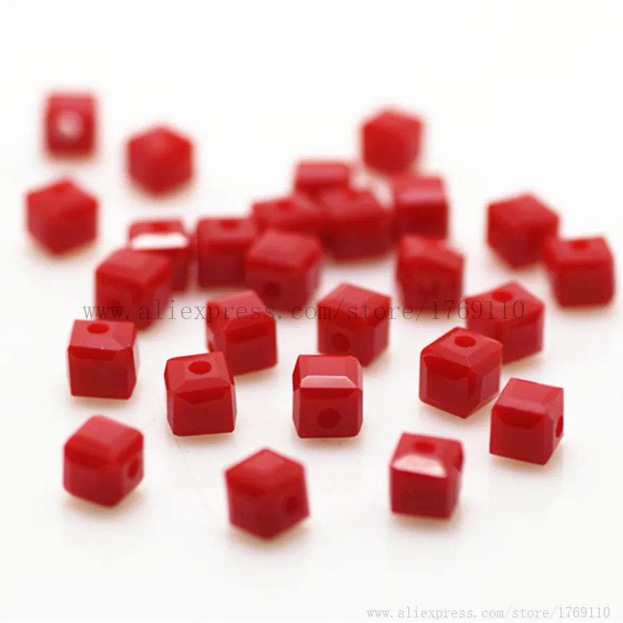 A pile of small, square-cut red glass crystal beads for jewelry making.