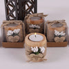 A collection of handcrafted wooden tealight candle holders tied with twine, used as wedding favors or gifts.