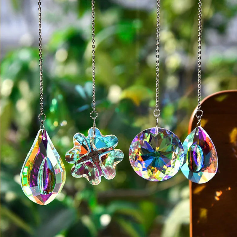 Three hanging crystal suncatchers shaped like flowers in iridescent colors suspended by chains