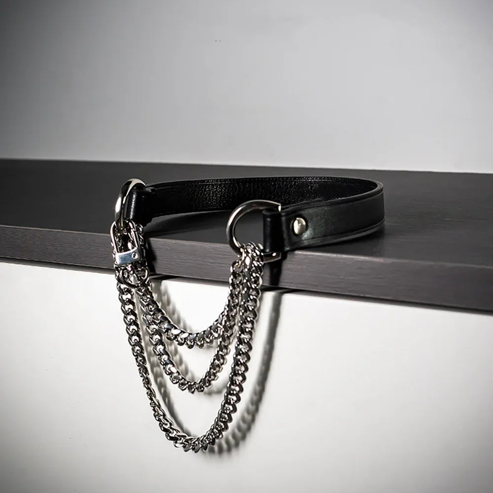 A black leather choker necklace featuring a triple-layer silver chain design displayed on a dark surface.