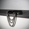 A black leather choker necklace featuring a triple-layer silver chain design displayed on a dark surface.