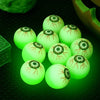 A collection of glow-in-the-dark Halloween eyeball bouncy balls resting on a dark green surface.