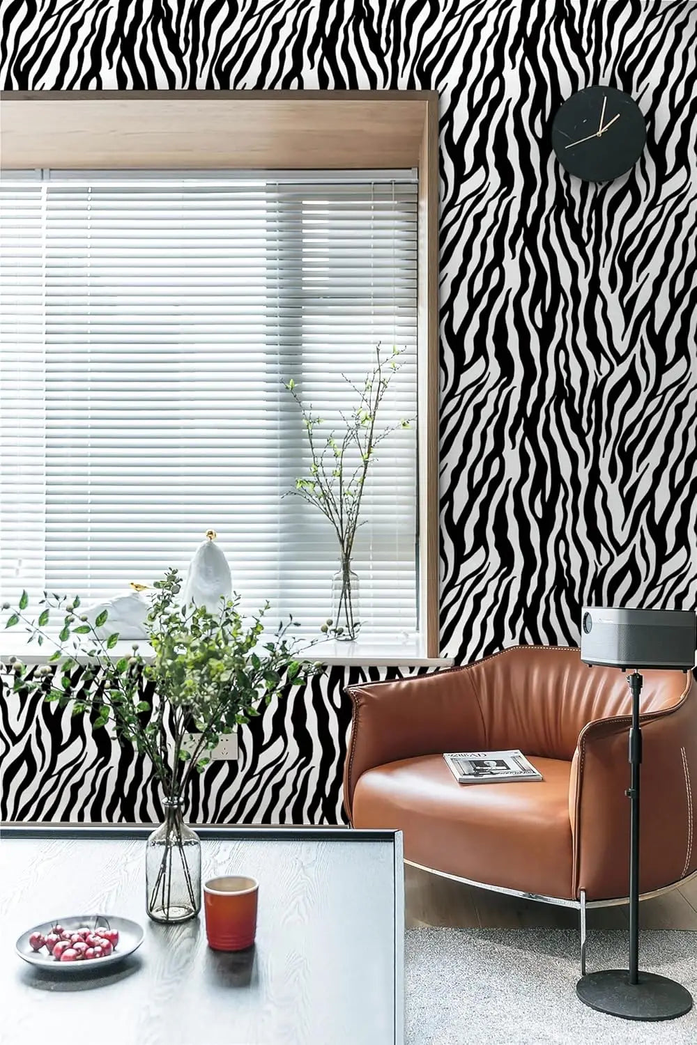 A modern interior featuring a brown leather armchair, a glass table, and black and white zebra print wallpaper.