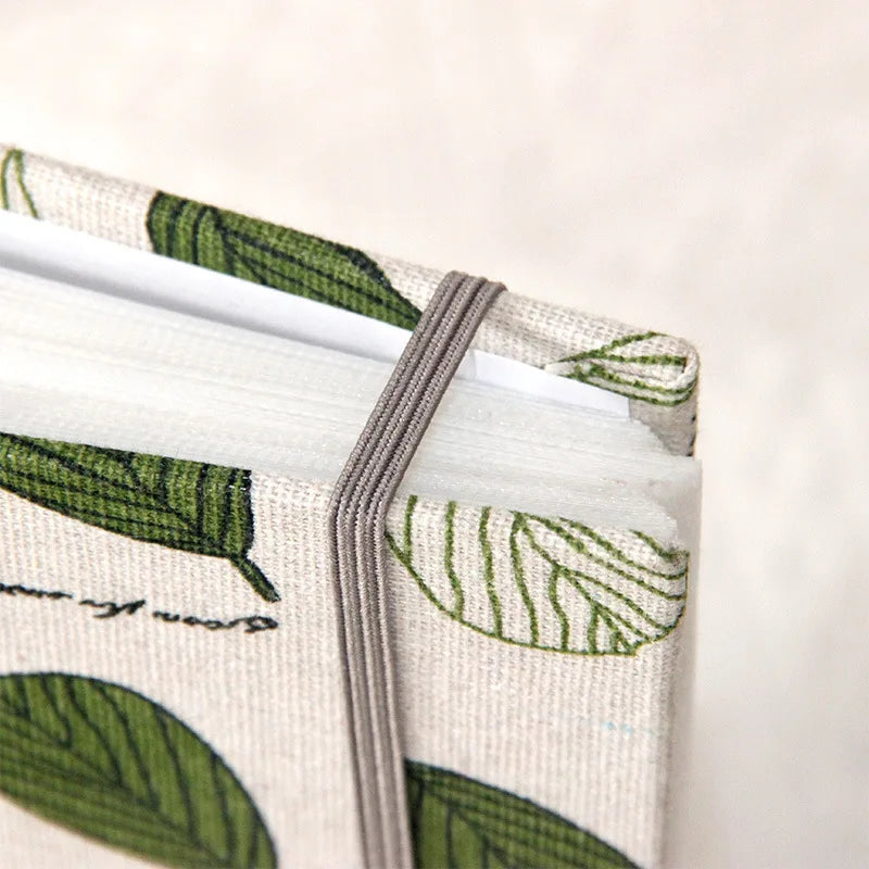 A close-up of a linen printed photo album with green leaf patterns and a gray binding.