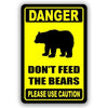 A yellow warning sign with black text that reads DANGER DON'T FEED THE BEARS PLEASE USE CAUTION