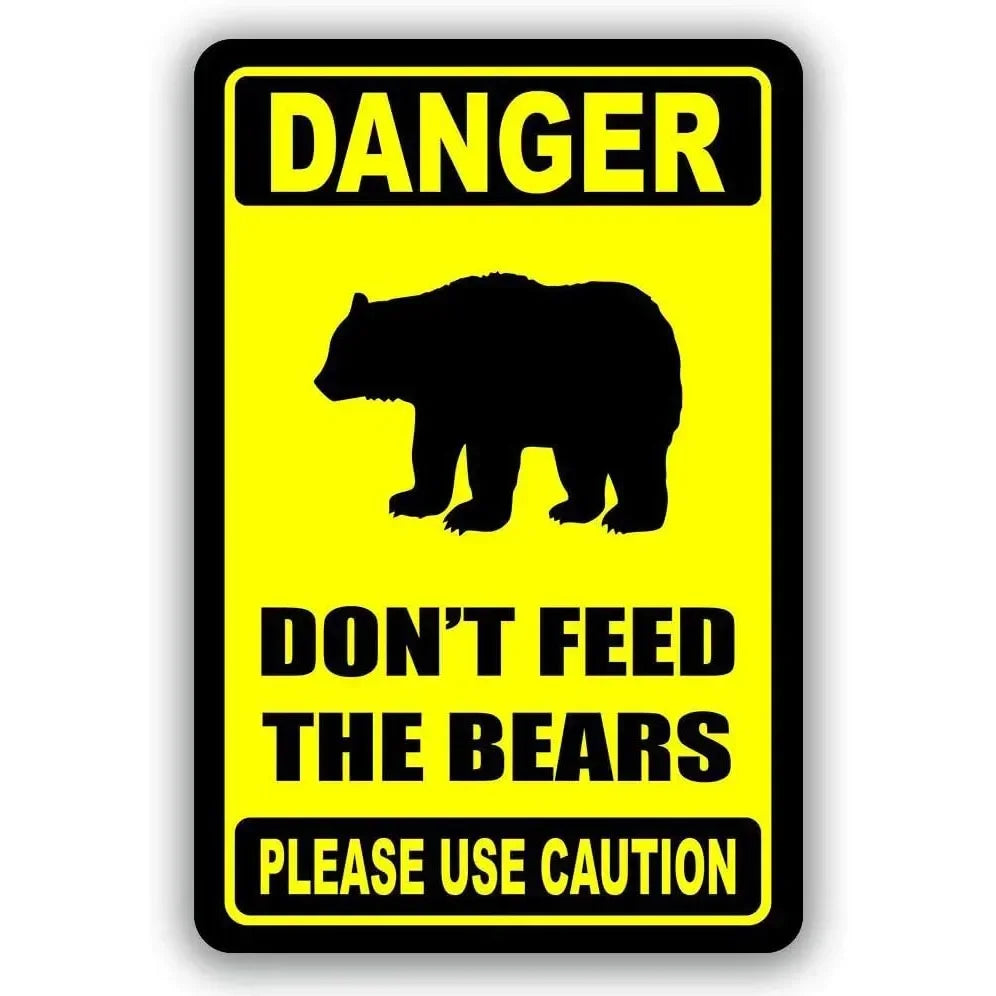 A yellow warning sign with black text that reads DANGER DON'T FEED THE BEARS PLEASE USE CAUTION