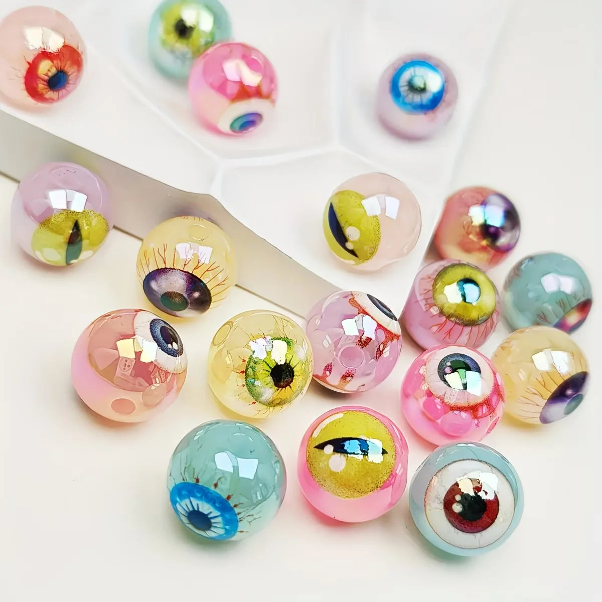A collection of glossy, double-sided eyeball beads in various pinks, greens, and blues for crafting.
