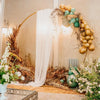 Elegant chiffon arch drapes with gold balloons and dried foliage for a wedding backdrop