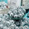 A pile of silver disco mirror balls used for party decor, displayed in a green bowl.