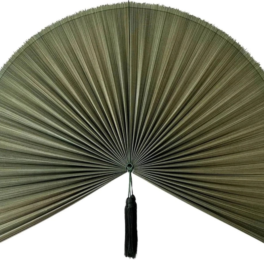 A handwoven bamboo wall fan decor with a wide, pleated fan and a black tassel.