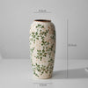 A tall ceramic milk pitcher with a pastoral green and beige floral design.