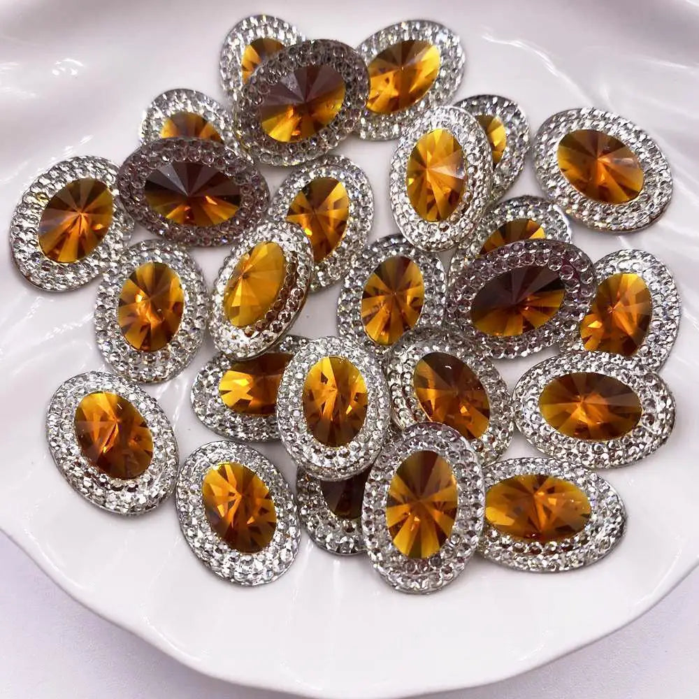 A collection of round, gold-toned gemstone flatback rhinestones set in silver-toned metal, displayed on a white plate.