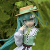 A PVC collectible figurine of Hatsune Miku with teal hair wearing a green outfit and straw hat.