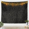 A dark tapestry wall hanging featuring a leopard print pattern illuminated by warm string lights.