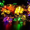 A close-up of solar decorative string lights with various colored, glowing floral shapes.