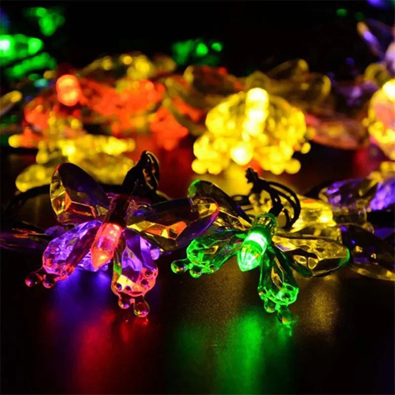 A close-up of solar decorative string lights with various colored, glowing floral shapes.