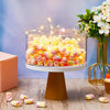 Clear acrylic cake display stands filled with colorful candies on a wooden surface.