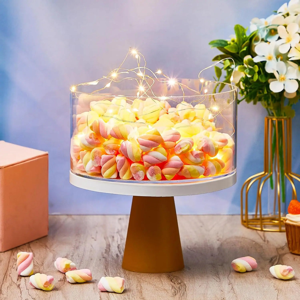 Clear acrylic cake display stands filled with colorful candies on a wooden surface.