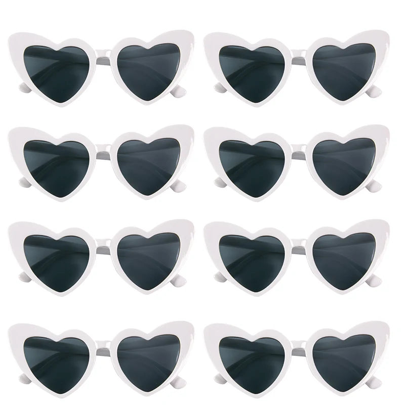 A set of heart-shaped sunglasses with black lenses and white frames.